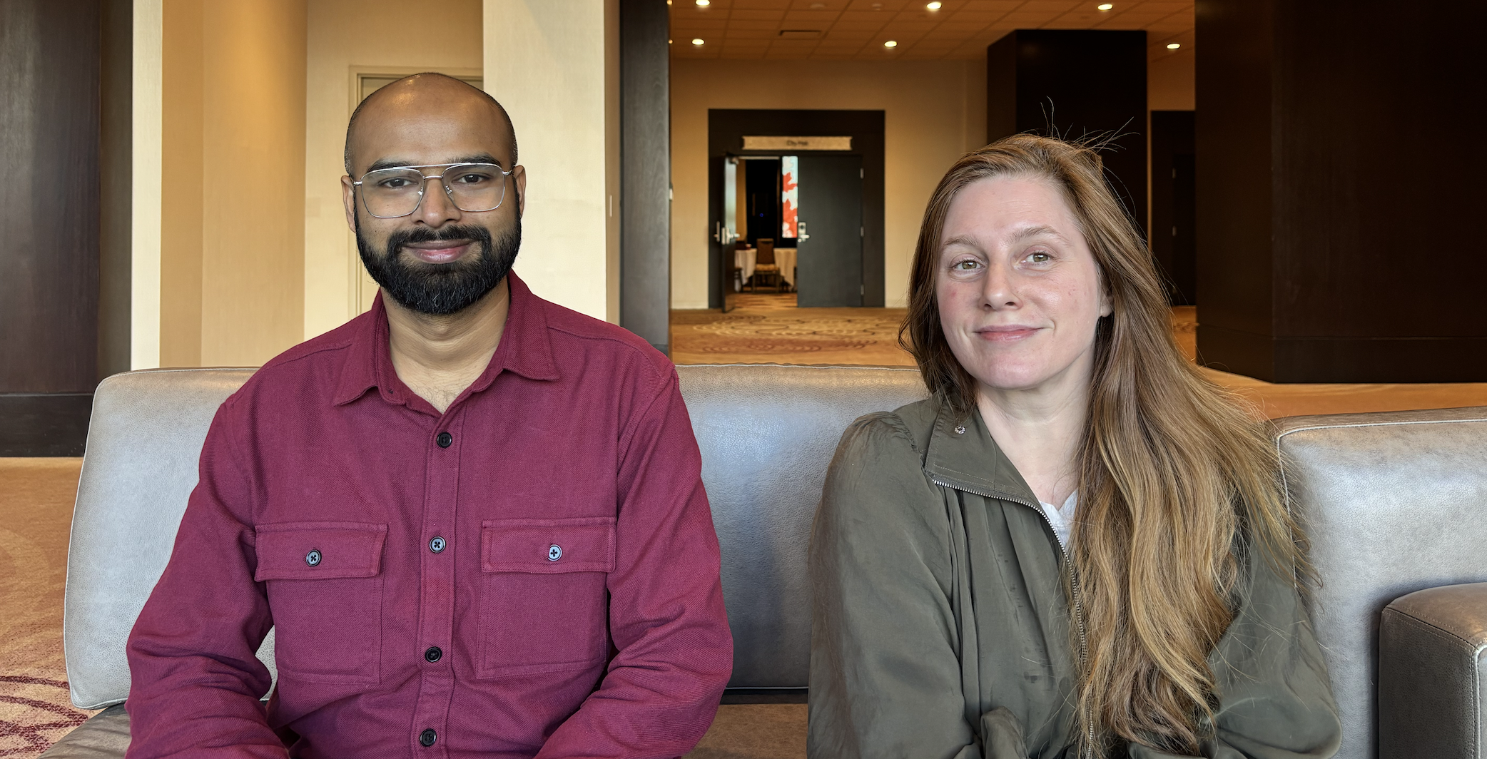 Santosh is an person of colour and wears glassed and has a beard he is wearing a red shirt and is smiling at camera. Jenny Tilson is a white woman and is wearing a green shirt and has long blonde hair and is smiling at camera.