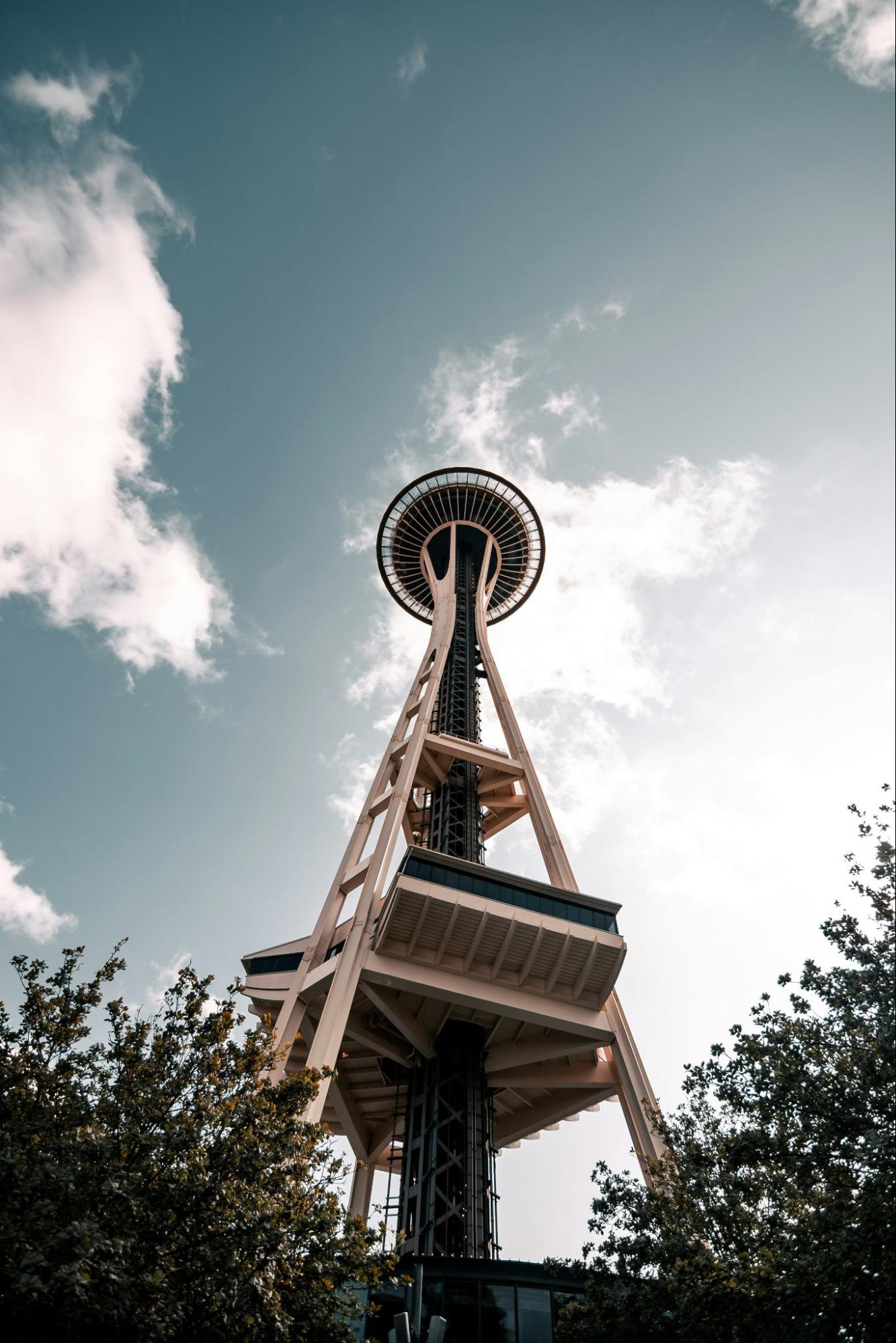 An almost vertical picture of the Space Needle from near its base, with the sky and clouds in the background.